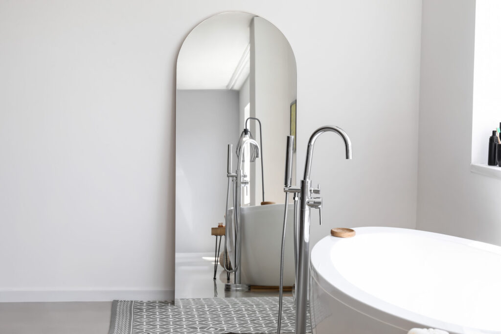Stylish interior of light bathroom with big mirror