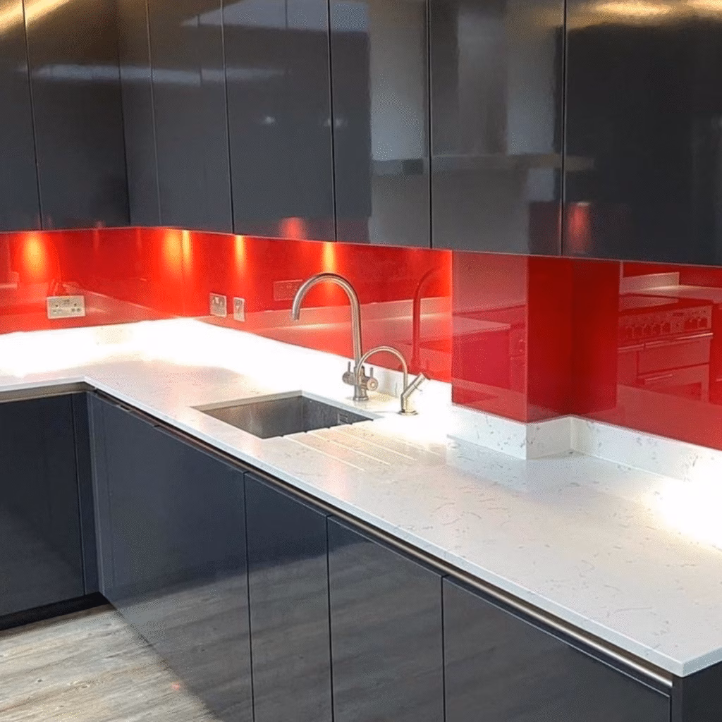 red painted glass splashbacks in a kitchen with dark grey cabinets and white worktops.